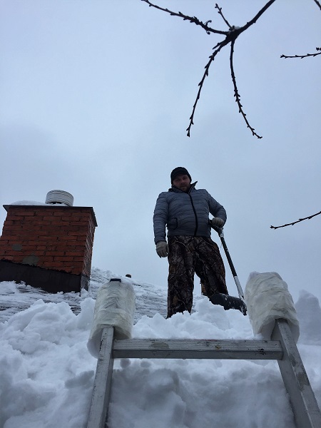 Snow looks nice but it has to be cleared, even from roofs.  Aleksei Volkov at work.